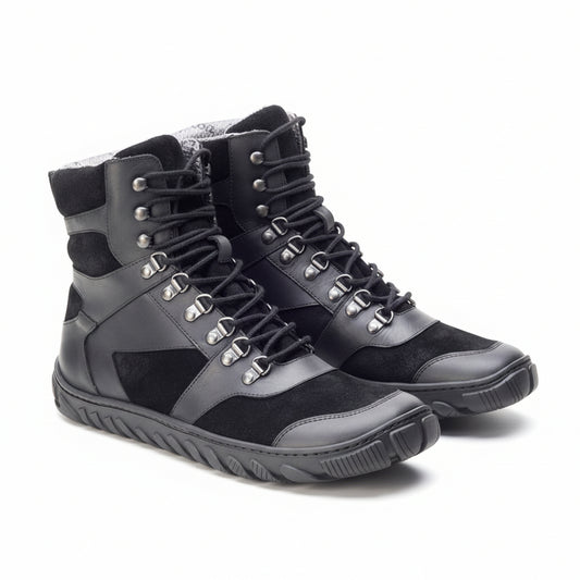 Lernen Sie die wasserdichten EXPLORER Black Boots von ZAQQ kennen: hohe Wanderschuhe aus Leder und Wildleder mit Metallösen, dicken Schnürsenkeln und robusten Gummisohlen. Sie sind perfekt für Abenteuer und werden in einem Dreiviertelwinkel präsentiert.