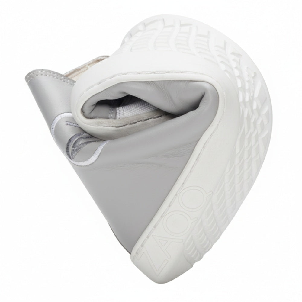 Ein CHUQQS Grey Sneaker von ZAQQ ist in der Mitte gefaltet, um seine Flexibilität zu demonstrieren. Der Schuh verfügt über eine strukturierte Sohle und aufwendige Nähte, wobei das ZAQQ-Logo an der Seite sichtbar ist.