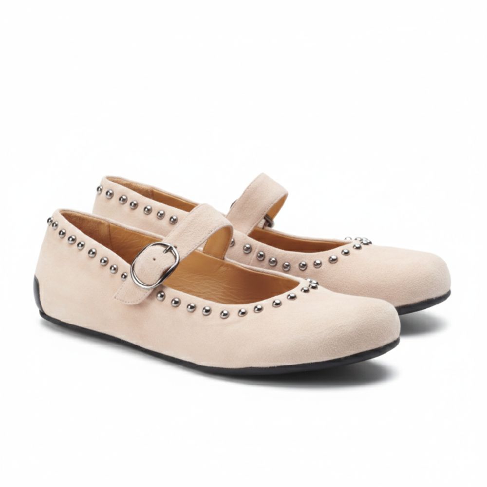 Die DIEQO Taupe von ZAQQ sind Mary Jane-Schuhe aus beigem Veloursleder, verziert mit silbernen Nieten an den Rändern. Diese Schuhe haben einen Riemen mit Schnalle an der Oberseite und eine flache schwarze Sohle, die pure Eleganz ausstrahlt.