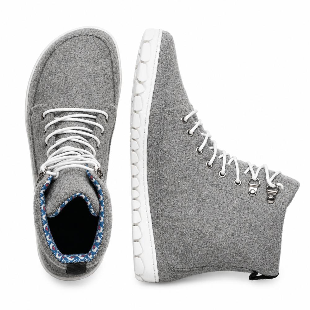 Vi presenterar QICE Grey från ZAQQ: Dessa sneakers har en high-top-design i grått med vita skosnören och erbjuder både en bra vy från ovan och från sidan. Deras framstående egenskap är en unikt strukturerad utomhussula som ger mer stil och komfort. De är tillverkade av material som liknar merinoull och erbjuder en iögonfallande blandning av komfort och mode.
