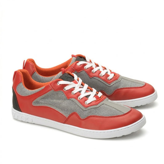 Ein Paar ZAQQ QOPA Red-Sneaker in Rot und Grau mit weißen Schnürsenkeln und orangefarbenen Akzenten. Diese atmungsaktiven Schuhe haben eine strukturierte Sohle und ein Mesh-Gewebe, um eine optimale Luftzirkulation zu gewährleisten. Sie werden elegant nebeneinander vor einem makellos weißen Hintergrund präsentiert.
