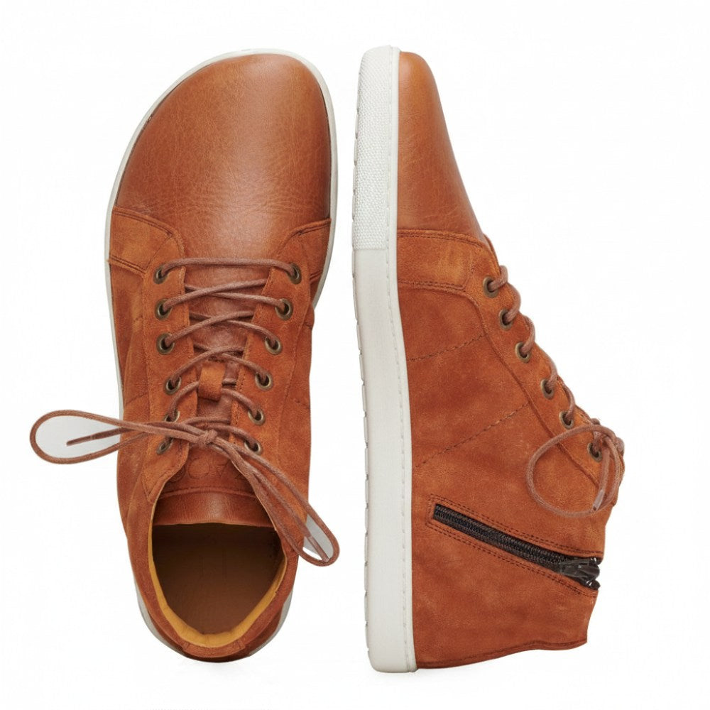 Der QORE Mid Sierra von ZAQQ präsentiert Eleganz als Paar High-Top-Sneaker aus braunem Leder mit weißer Sohle. Ein Sneaker ist von oben mit teilweise geöffneten Schnürsenkeln zu sehen, während der andere von der Seite betrachtet wird und ein Reißverschlussdetail und den Markennamen ZAQQ auf der Sohle hervorhebt.