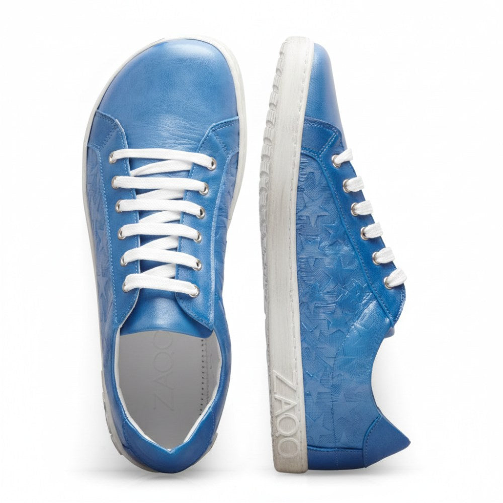 Ein Paar SLOQ Stars Blue Sneaker aus Nappaleder mit weißen Schnürsenkeln und Sohlen, von oben und von der Seite zu sehen. Der linke Schuh hat den Markennamen ZAQQ auf der Sohle eingeprägt. Diese Barfußschuhe haben an den Seiten ein strukturiertes Muster für noch mehr Stil.