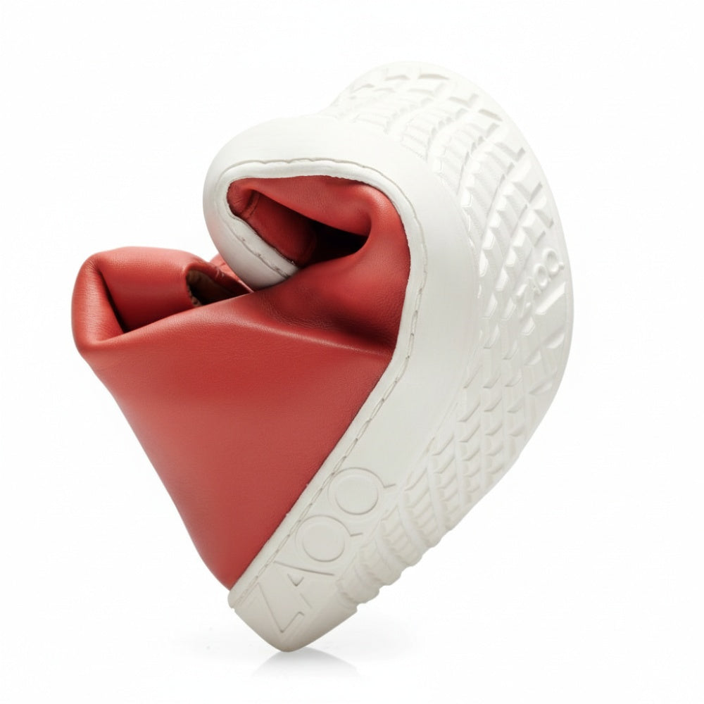 Ein einzelner SNAQ Red High Top Sneaker ist kunstvoll zu einer Spirale gedreht, was seine beeindruckende Flexibilität unterstreicht, und verfügt über eine dicke, strukturierte weiße Sohle. Dieses Design mit dem geprägten Markennamen ZAQQ verbindet auf innovative Weise nahtlos Komfort und Stil.