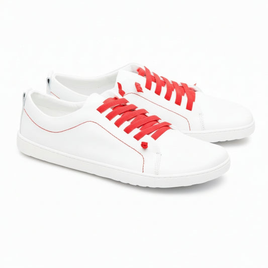 Wir präsentieren den STIQ White von ZAQQ, ein stylisches Paar Sneaker aus hochwertigem Nappaleder. Diese eleganten weißen Schuhe sind mit leuchtend roten Schnürsenkeln und Nähten akzentuiert. Sie haben eine graue, strukturierte Sohle und das dezente ZOO-Logo ist elegant auf der Ferse eingeprägt. Nebeneinander vor einem schlichten weißen Hintergrund präsentiert, verkörpern sie perfekt zeitgenössische Mode.