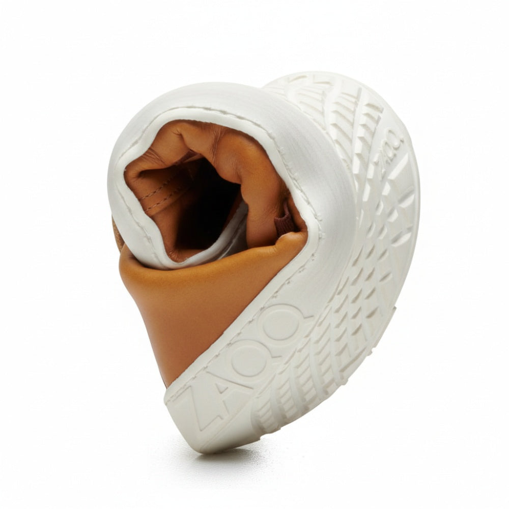 Der STRAQ Sierra, ein flexibler Schuh von ZAQQ, ist spiralförmig gebogen, um sein Sohlenmuster und das Obermaterial aus sattem braunem Nappaleder zur Geltung zu bringen, wobei der Markenname elegant auf der Seite dieses stylischen Barfuß-Sneakers prangt.