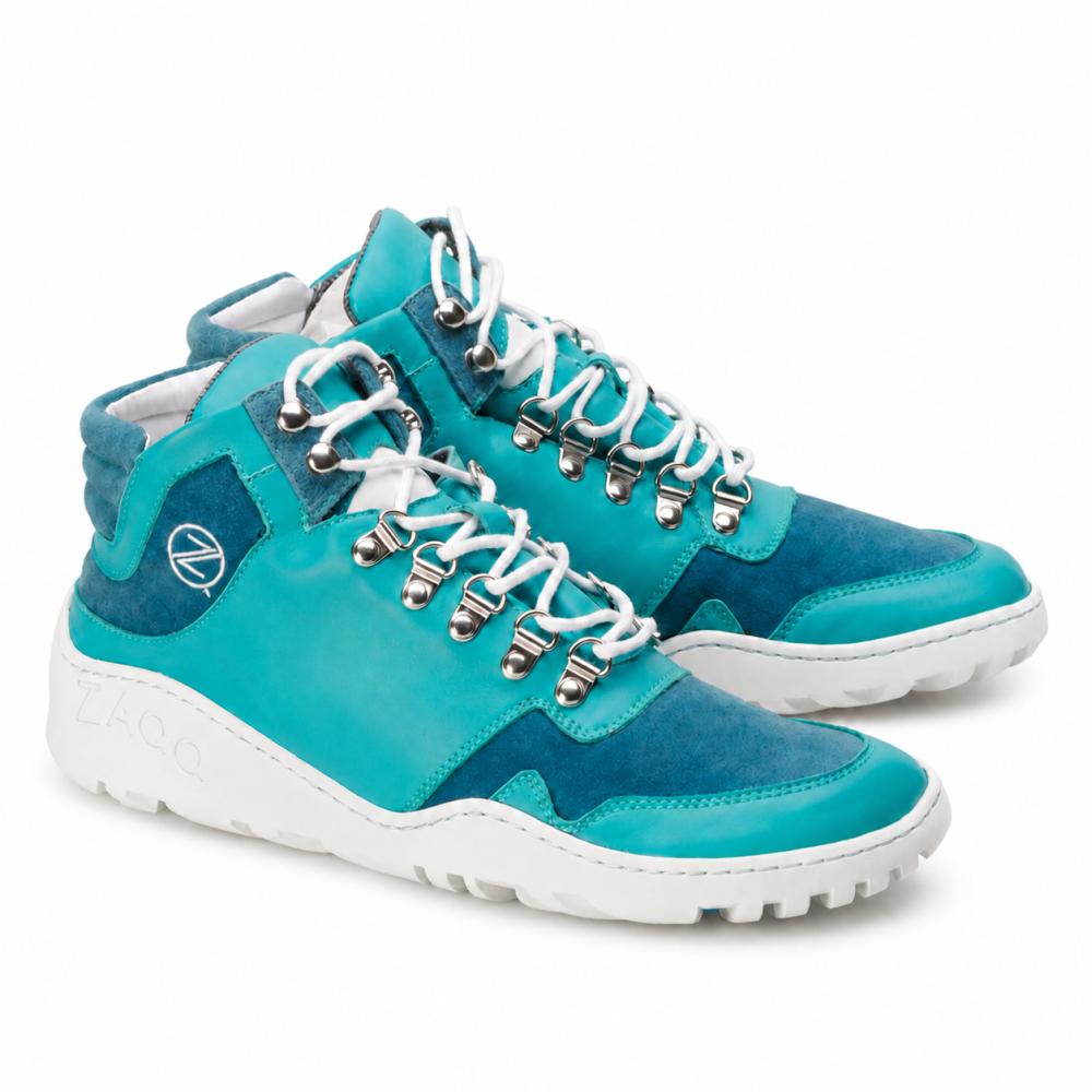 Ett par vattentäta VAQATION Blue High-Top-sneakers från ZAQQ med vita skosnören och en TERRA-sula. Dessa stiliga skor har silverfärgade öljetter och en liten rund logotyp på sidan och kombinerar släta och mockaytor för extra stil och komfort.